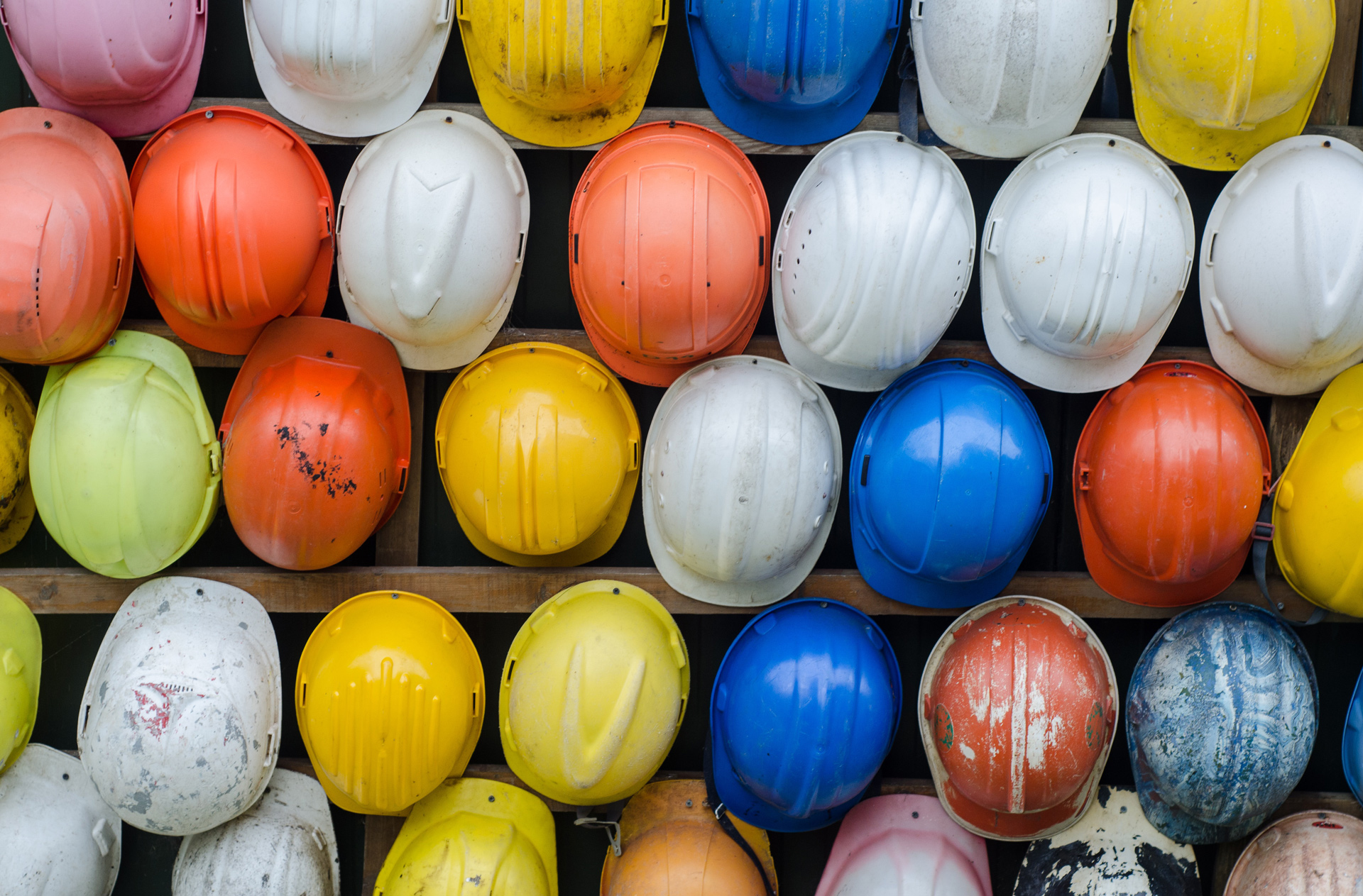 image of lots of colourful hard hats hung on a peg board